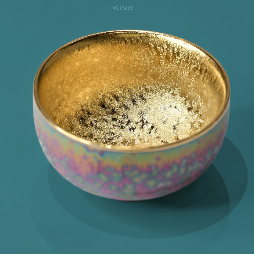 A handcrafted ceramic tea cup with a radiant gilded interior and ever-changing kiln-fired colors.